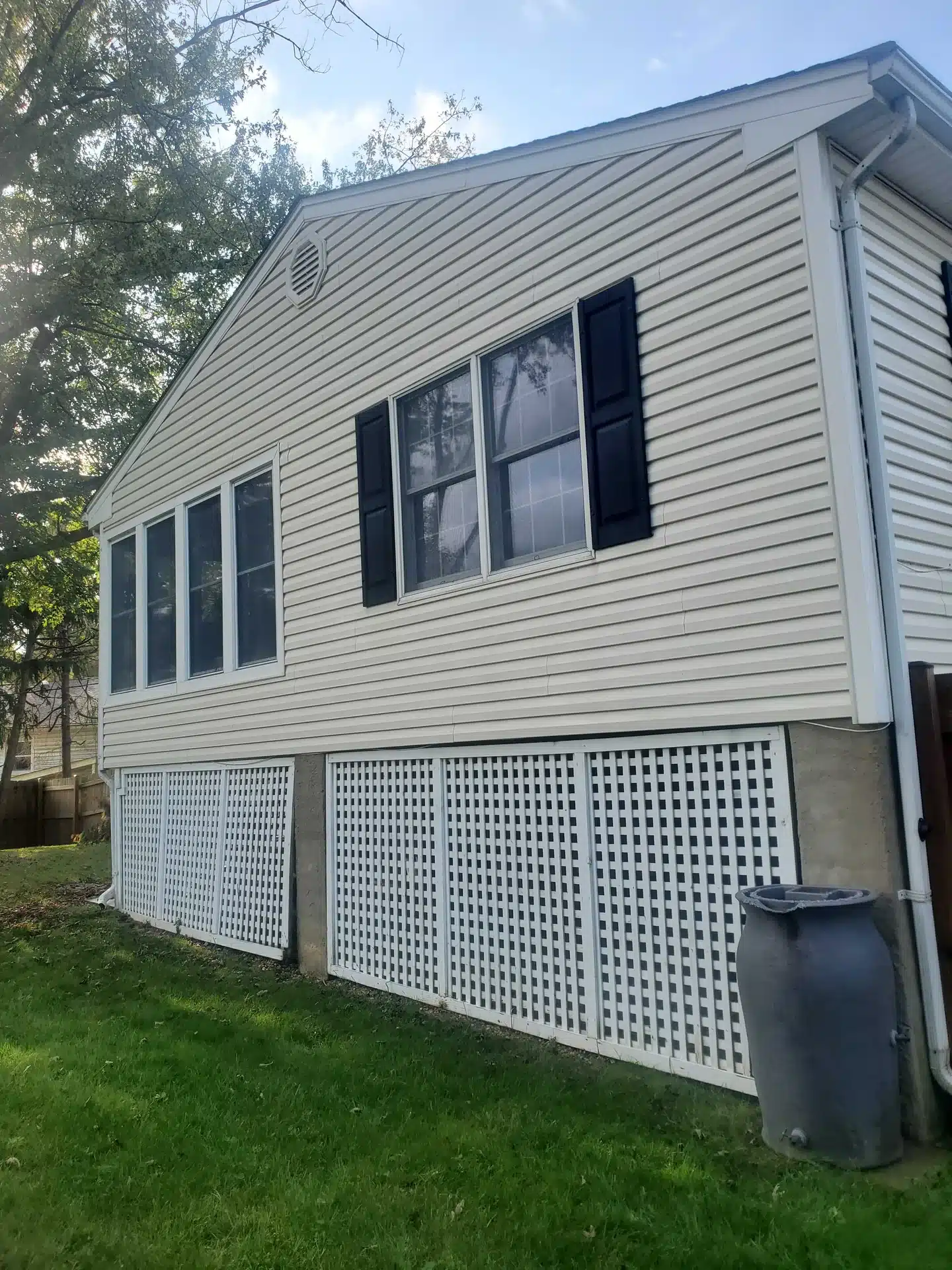 Vinyl siding and white lattice on an enclosed porch after cleaning.
